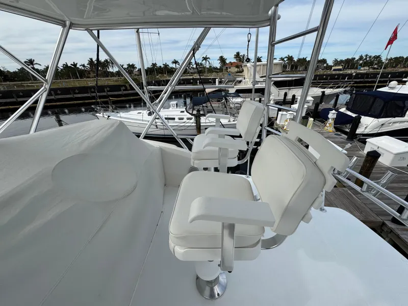 Slide: The Image of 1999 Cabo 45 Express yacht with white seating on the deck, docked at a marina. - 27