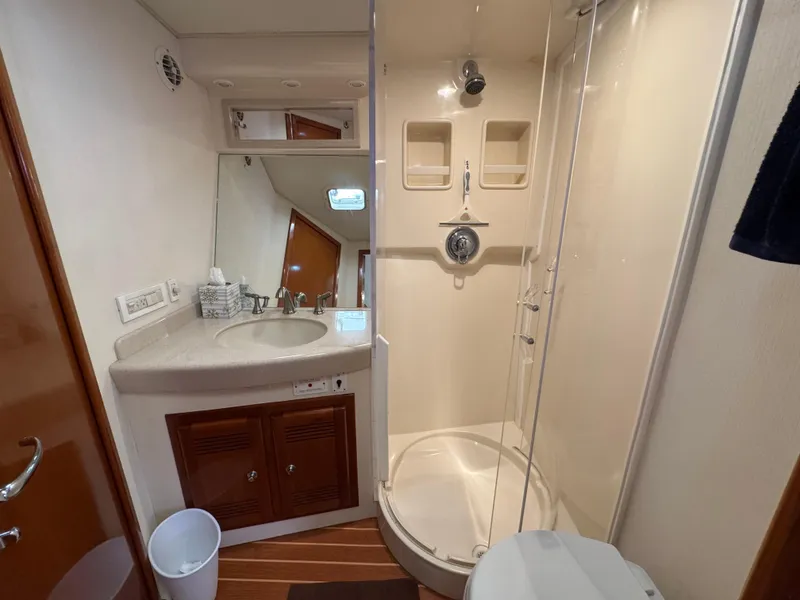 Slide: The Image of 1999 Cabo 45 Express yacht bathroom with shower, sink, and wooden cabinetry. - 41