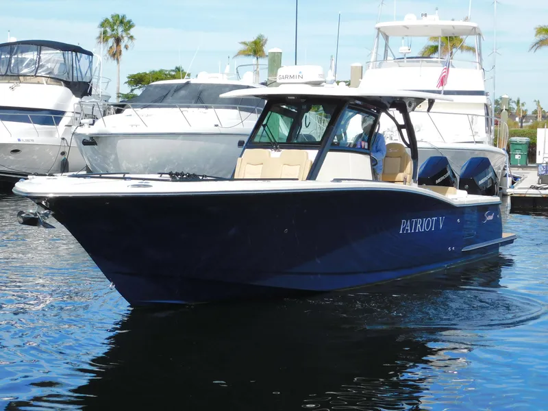 Slide: The Image of 2024 Scout 33LXF boat docked in marina, sleek design, blue hull. - 0