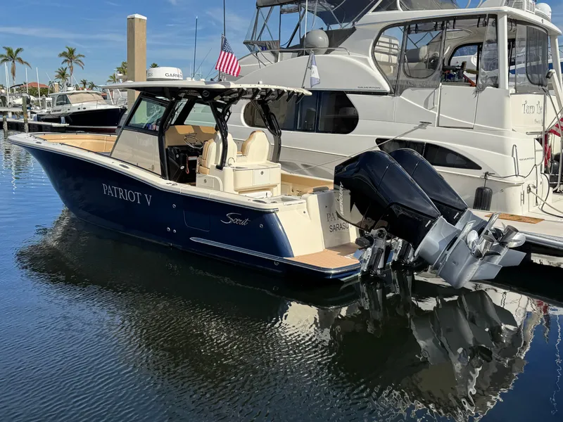 Slide: The Image of 2024 Scout 33LXF boat docked in marina, featuring dual outboard engines. - 1