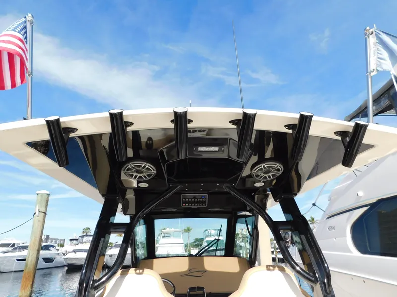 Slide: The Image of 2024 Scout 33LXF boat with T-top and speakers, docked at marina. - 18