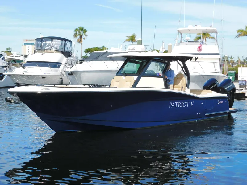 Slide: The Image of 2024 Scout 33LXF boat docked in marina, featuring sleek design and dual engines. - 2