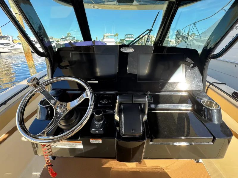 Slide: The Image of 2024 Scout 33LXF boat helm with dual screens and steering wheel. - 21
