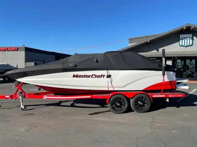 Slide: The Image of 2020 MasterCraft XT22 boat on red trailer, covered, parked outside dealership. - 20