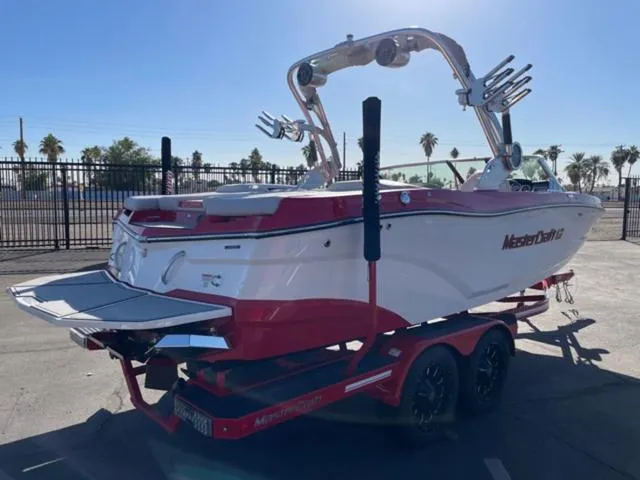 Slide: The Image of 2020 MasterCraft XT22 boat on trailer, red and white design, parked outdoors. - 6