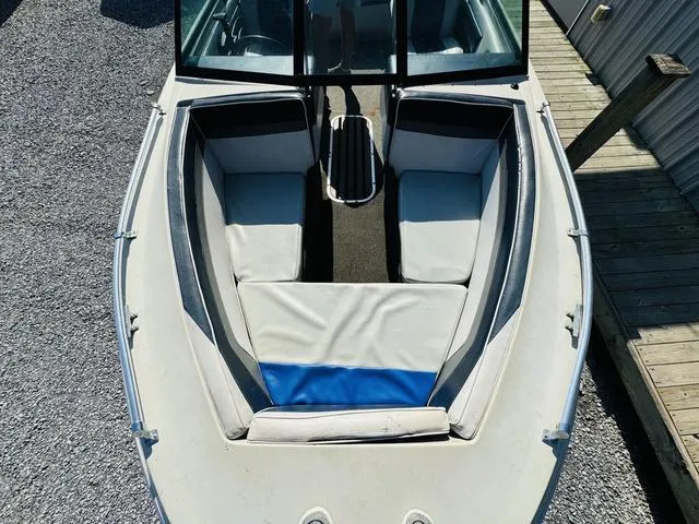 Slide: The Image of 1989 Glassport 175 BR boat interior with white and blue seating, docked on gravel. - 11
