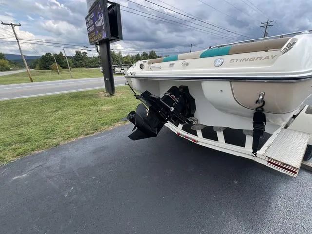 Slide: The Image of 2002 Stingray 200LS/LX boat on trailer, parked on asphalt near grassy area. - 10