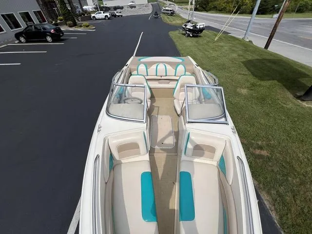 Slide: The Image of 2002 Stingray 200LS/LX boat with teal and beige interior, parked on asphalt near grass. - 11
