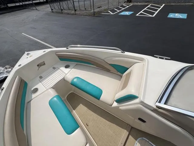 Slide: The Image of 2002 Stingray 200LS/LX boat interior with teal and beige seating, docked in parking area. - 12