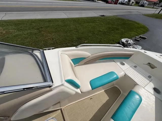 Slide: The Image of 2002 Stingray 200LS/LX boat interior with teal and white seating, parked near a road. - 13