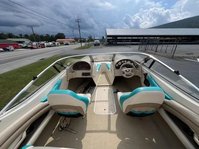 Slide: The Image of 2002 Stingray 200LS/LX boat interior with teal and beige seating, parked near a road. - 7