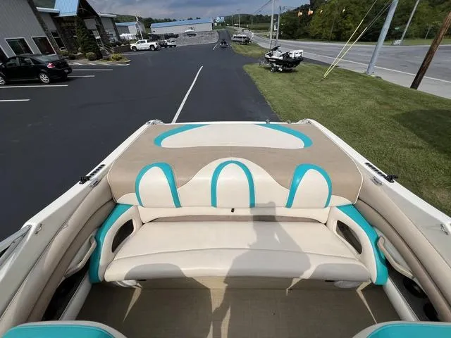 Slide: The Image of 2002 Stingray 200LS/LX boat interior with beige and turquoise seating, parked near a road. - 8
