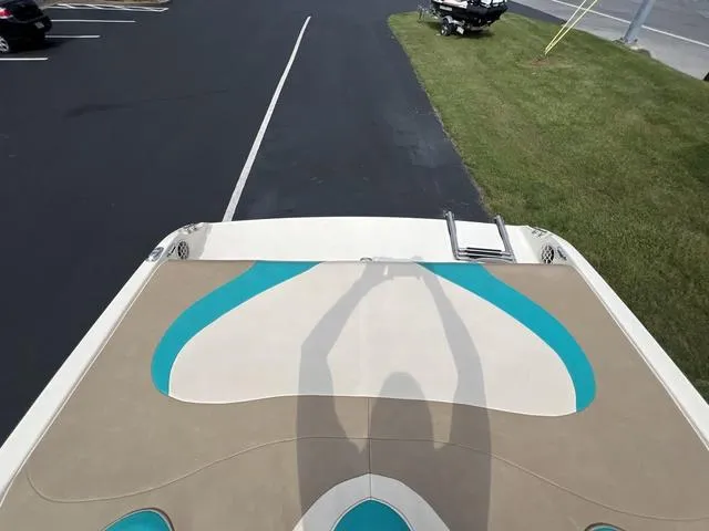 Slide: The Image of 2002 Stingray 200LS/LX boat with teal and beige deck design, parked on asphalt. - 9