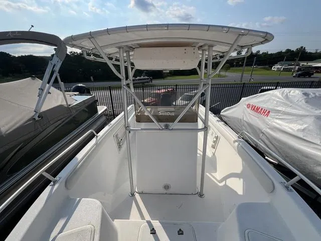 Slide: The Image of 2001 Carolina Skiff 2100 boat with T-top, docked alongside other boats. - 12