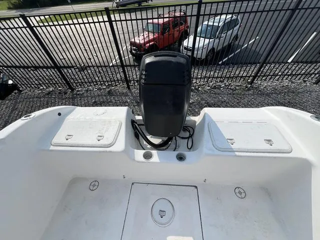 Slide: The Image of 2001 Carolina Skiff 2100 boat with outboard motor, parked near a fence. - 6