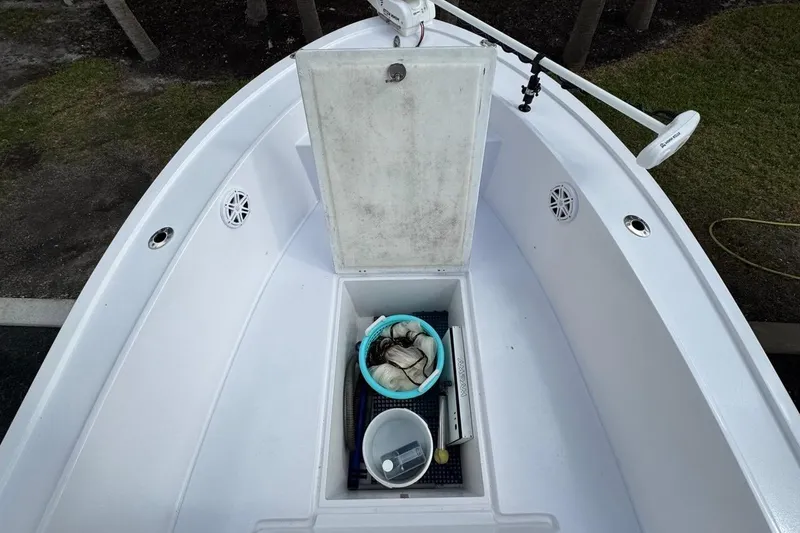 Slide: The Image of 1986 Mako 224 CC boat deck with open storage compartment and fishing gear. - 22