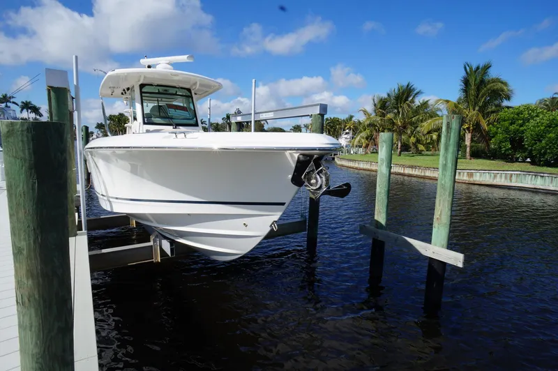 Slide: The Image of 2017 Boston Whaler 330 Outrage boat docked on a lift by the water. - 2