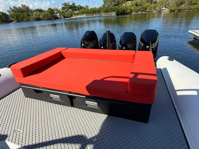 Slide: The Image of 2024 Goldfish 46 Open boat with red seating and four outboard engines on a calm lake. - 10