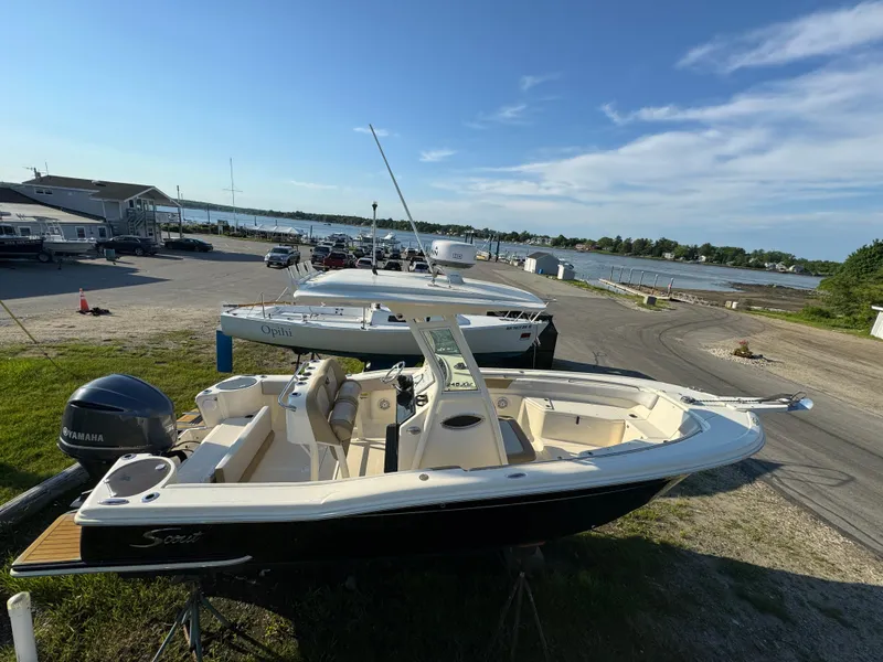 Slide: The Image of 2014 Scout 245 XSF boat docked near a scenic waterfront. - 10