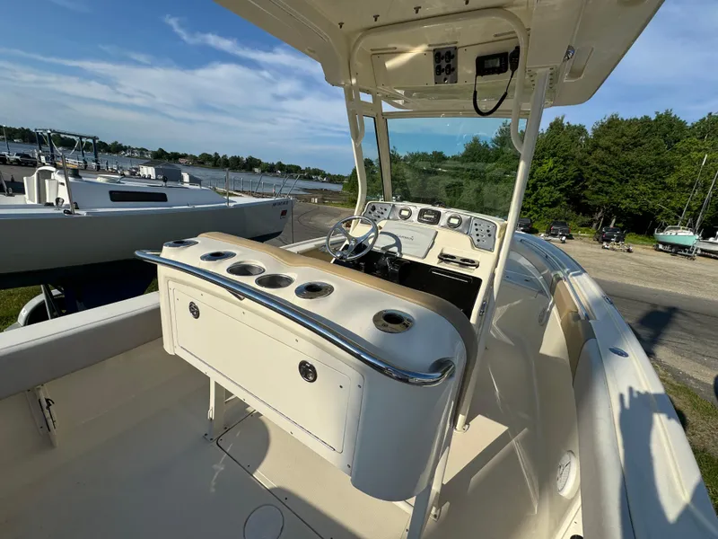 Slide: The Image of 2014 Scout 245 XSF boat with spacious deck and modern console, docked near a marina. - 19