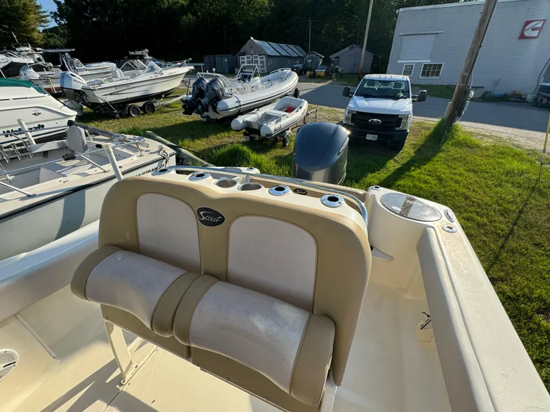 Slide: The Image of 2014 Scout 245 XSF boat interior with seating and motor, parked outdoors. - 21