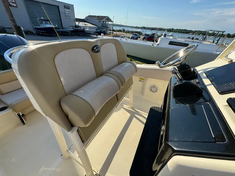 Slide: The Image of 2014 Scout 245 XSF boat interior with helm and seating, docked near marina. - 23