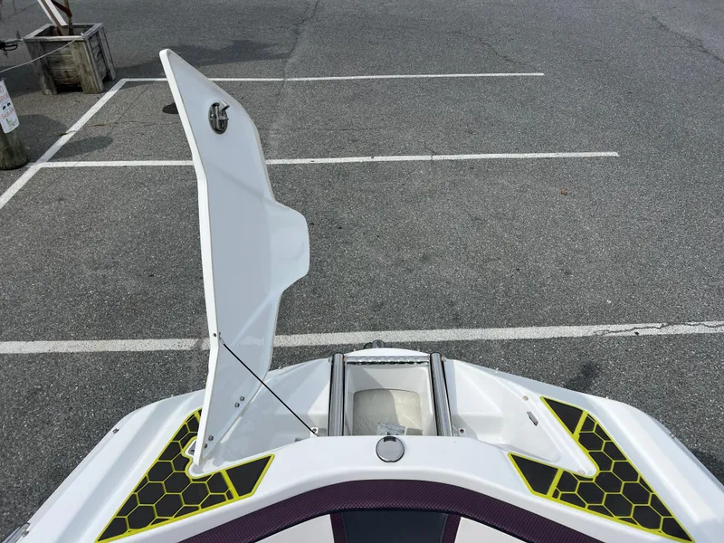 Slide: The Image of 2020 Scarab 215ID boat with open storage compartment in a parking lot. - 4
