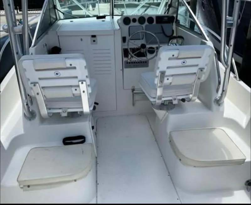 Slide: The Image of 1995 Pursuit 2470 boat interior with dual white seats and steering console. - 11