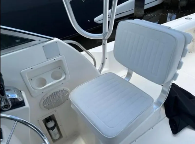 Slide: The Image of 1995 Pursuit 2470 boat interior with white cushioned seat and steering area. - 12