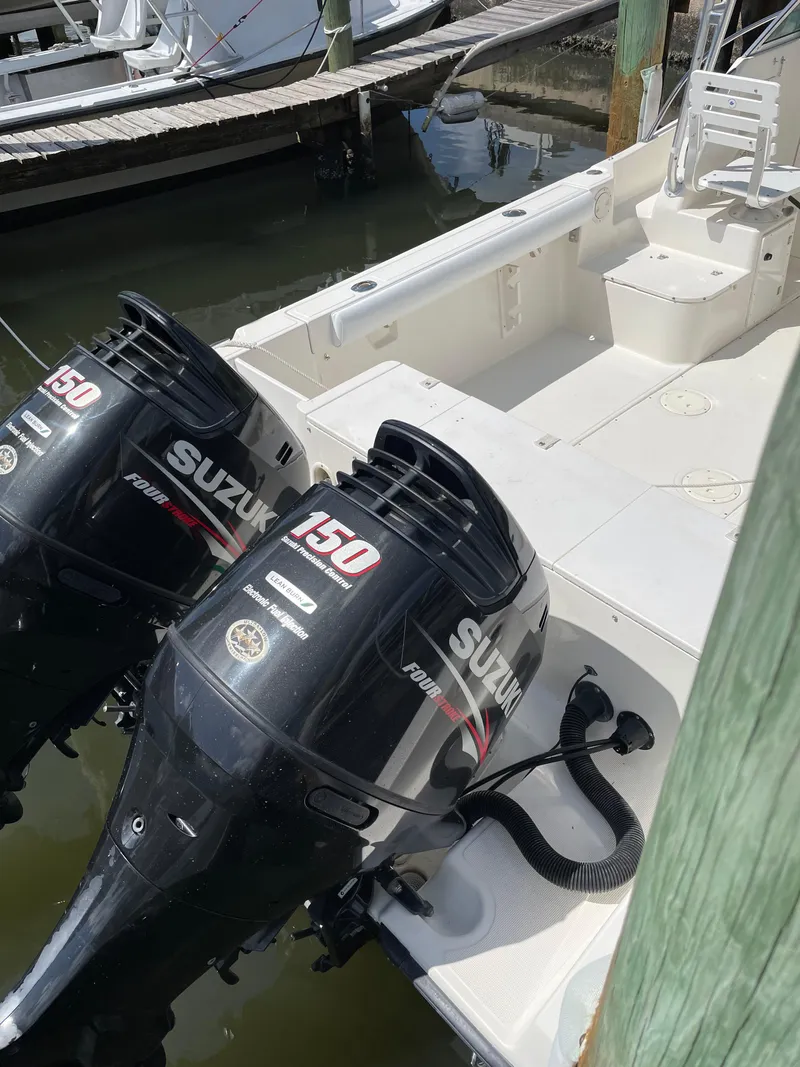 Slide: The Image of 1995 Pursuit 2470 boat with twin Suzuki 150 outboard motors docked at marina. - 19