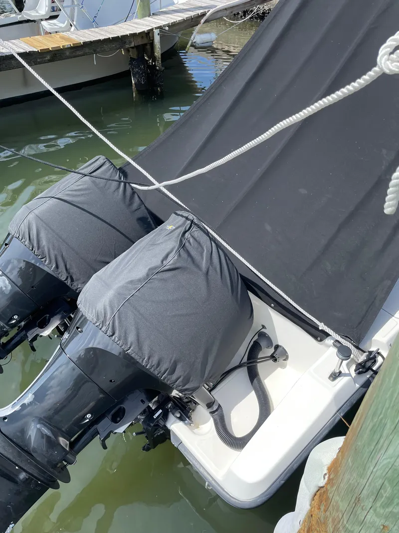 Slide: The Image of Twin outboard motors on a 1995 Pursuit 2470 boat, docked with protective covers. - 21