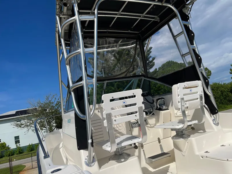 Slide: The Image of 1995 Pursuit 2470 boat with dual white seats and metal frame under a blue sky. - 23