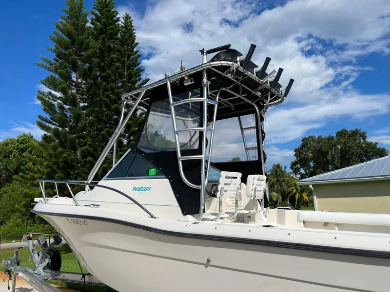 Slide: The Image of 1995 Pursuit 2470 boat with T-top, parked outdoors under a clear blue sky. - 3