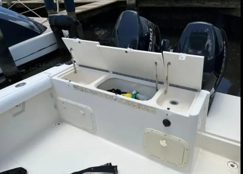 Slide: The Image of 1995 Pursuit 2470 boat with open storage compartment and dual outboard motors. - 4