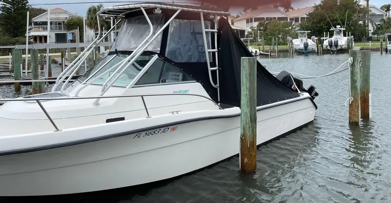 Slide: The Image of 1995 Pursuit 2470 boat docked in marina, covered with black tarp. - 5