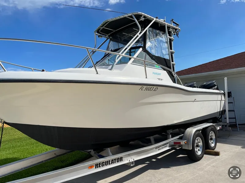 Slide: The Image of 1995 Pursuit 2470 boat on trailer, parked outdoors under clear blue sky. - 6