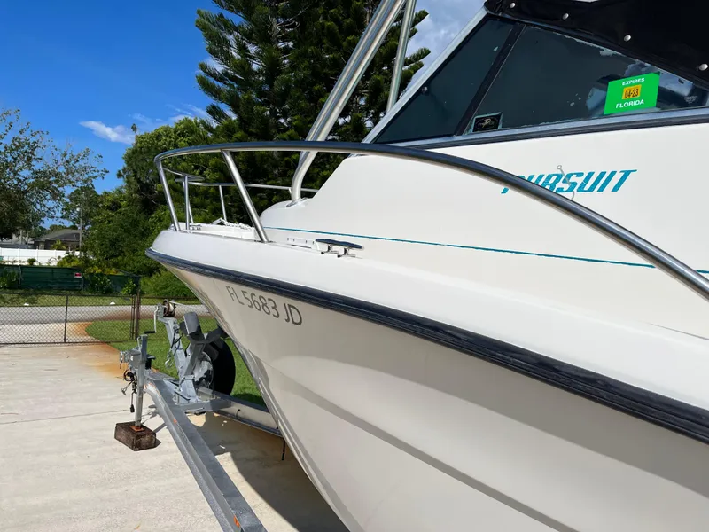 Slide: The Image of 1995 Pursuit 2470 boat on trailer, Florida registration, sunny day, green trees in background. - 7