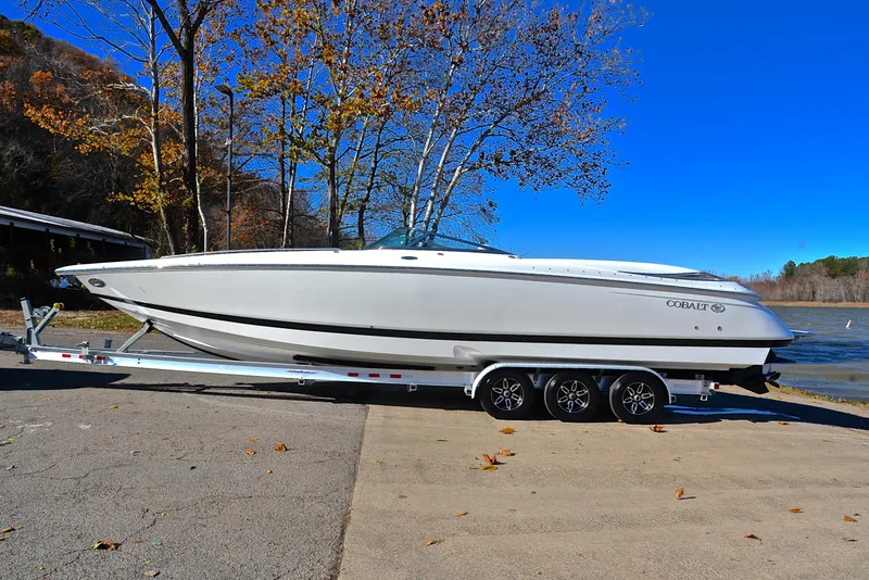 Slide: The Image of 2005 Cobalt 343 boat on trailer by lakeside, clear blue sky background. - 15