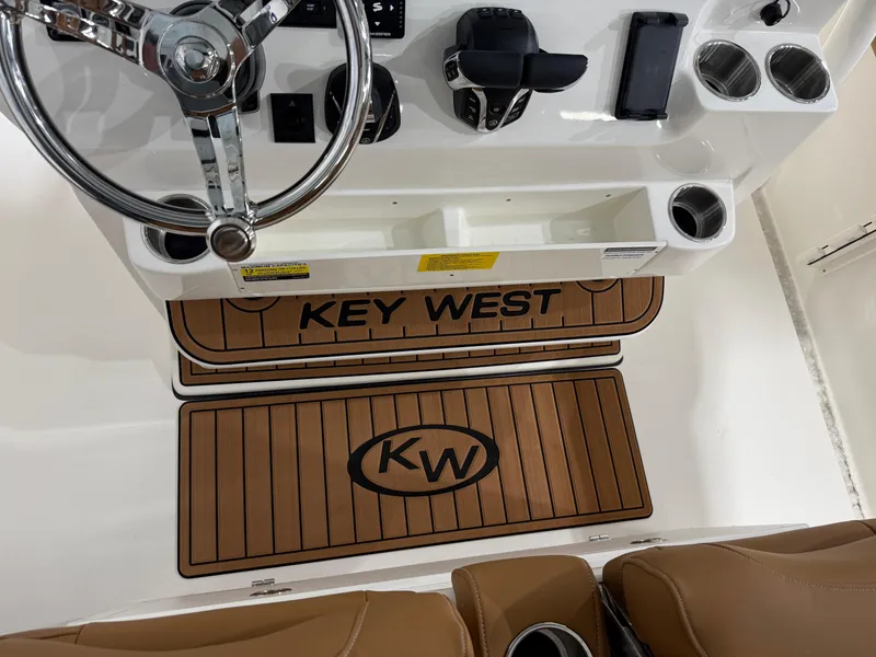 Slide: The Image of 2025 Key West 291FS boat cockpit with steering wheel and branded floor mats. - 27