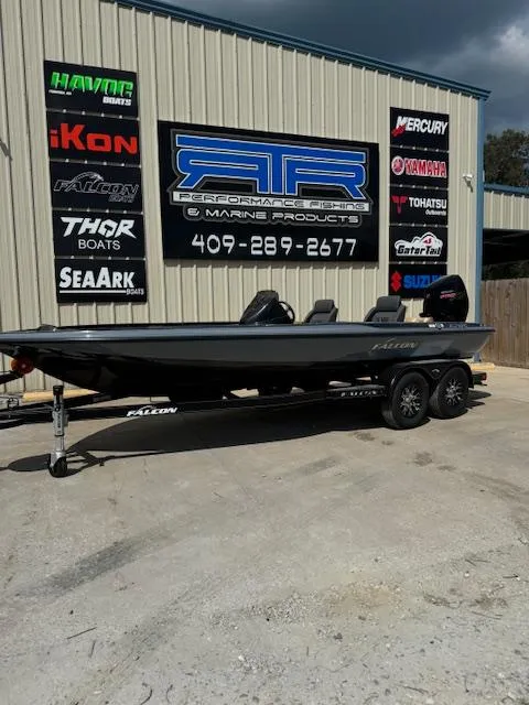 The Image of 2025 Falcon F205 boat on trailer outside marine shop with various brand logos. - 0
