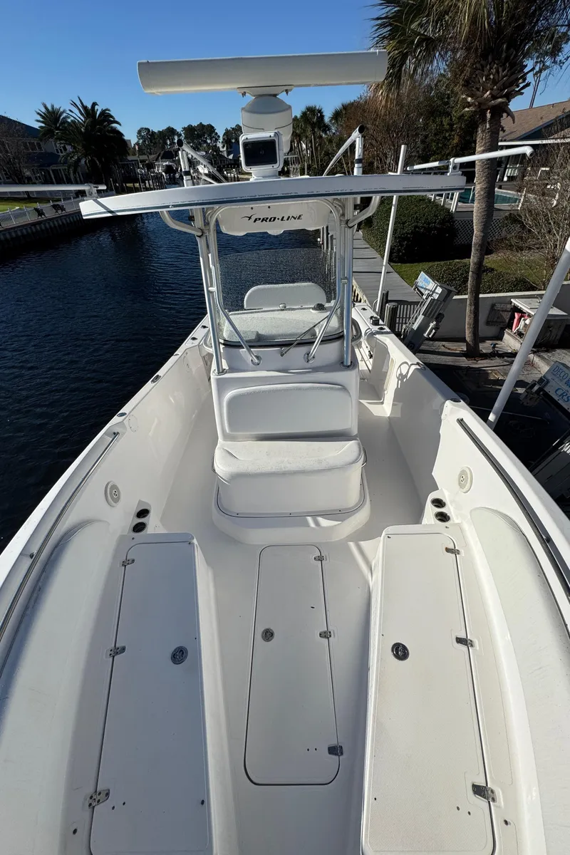 Slide: The Image of 2007 Pro-Line 29 Super Sport boat with spacious deck and seating, docked by palm trees. - 31