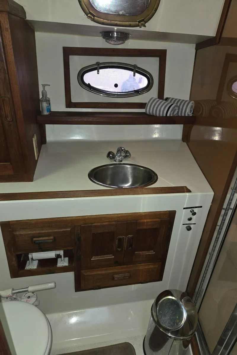 Slide: The Image of 1991 Cooper Prowler boat bathroom with sink, wooden cabinets, and porthole window. - 21
