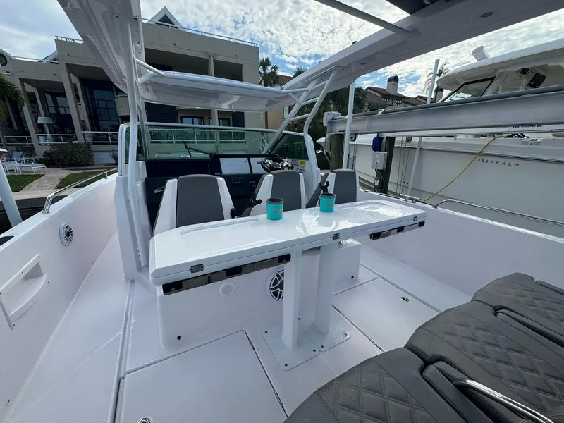 Slide: The Image of 2021 Axopar 37ST boat interior with seating and table, docked near modern buildings. - 16