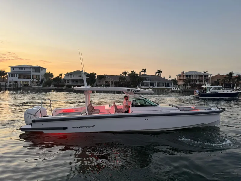 Slide: The Image of 2021 Axopar 37ST boat cruising at sunset near waterfront homes. - 2