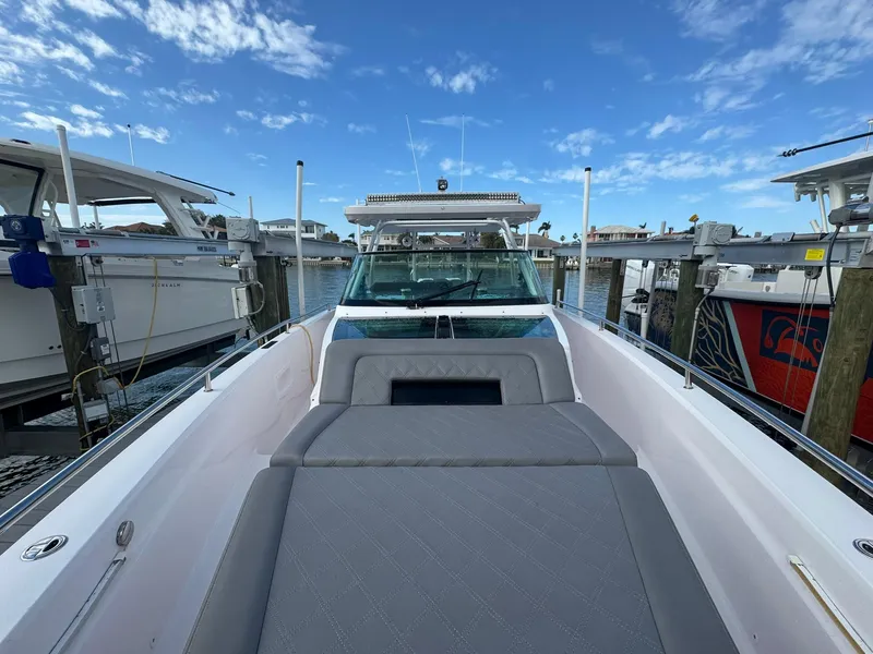 Slide: The Image of 2021 Axopar 37ST boat docked, featuring spacious deck and sleek design under blue sky. - 22