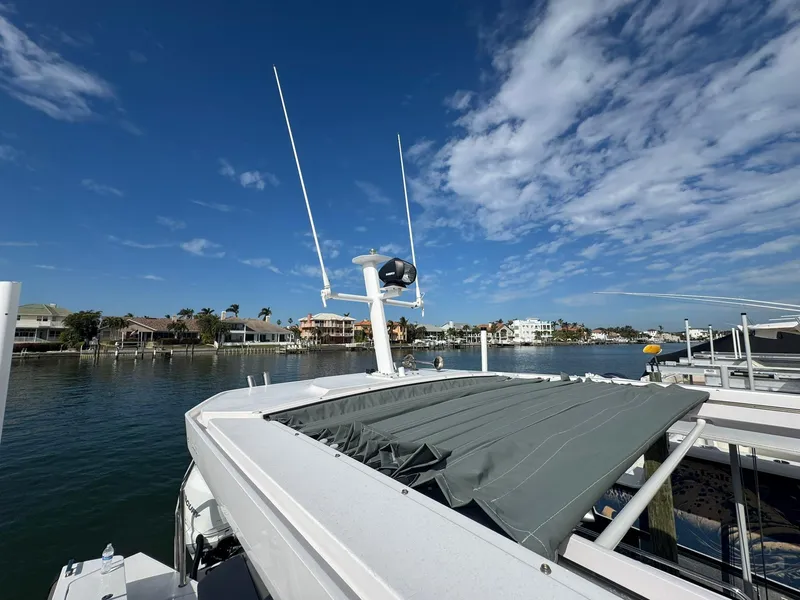 Slide: The Image of 2021 Axopar 37ST boat with antennas, docked by waterfront homes under a blue sky. - 34