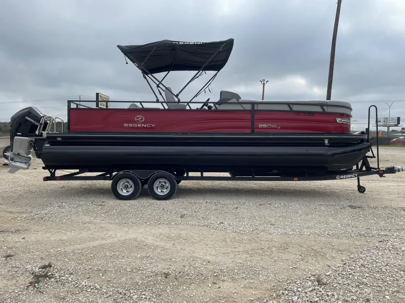 The Image of 2023 Regency 250 DL3 pontoon boat on trailer, red and black design. - 0