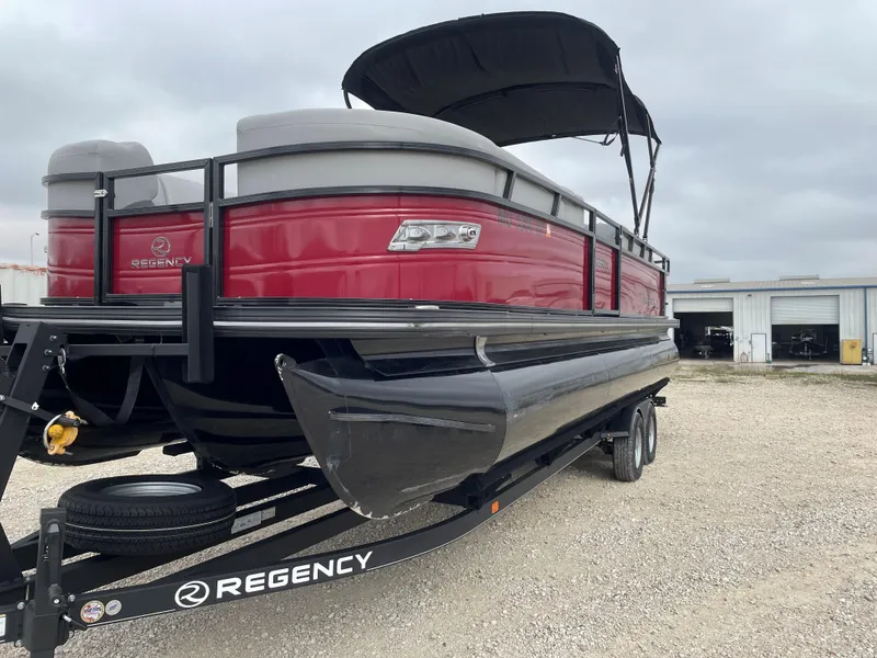 Slide: The Image of 2023 Regency 250 DL3 pontoon boat with red exterior and black canopy on trailer. - 6