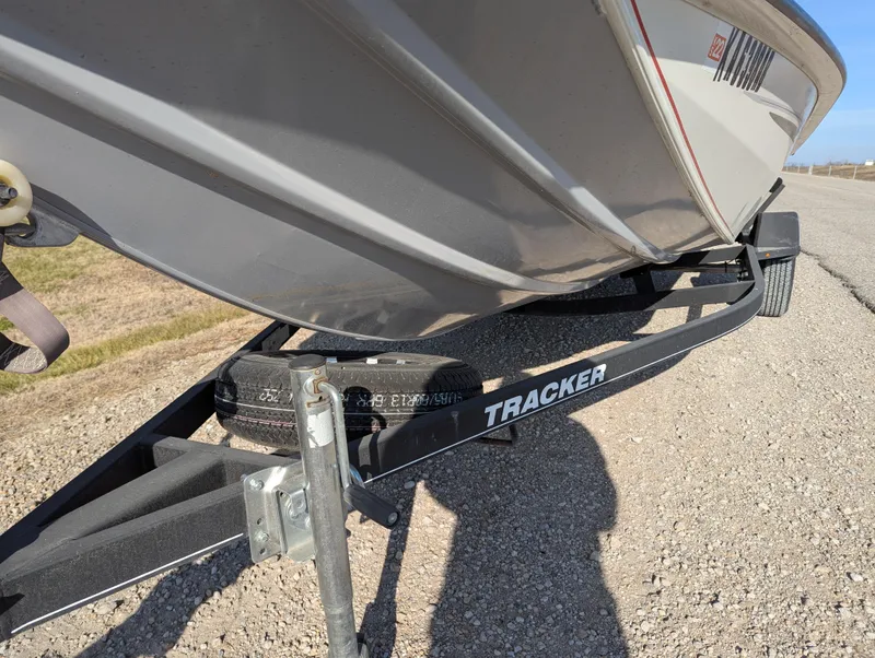 Slide: The Image of 2019 Tracker Pro Team 195 TXW Tournament Edition boat on trailer, parked on gravel. - 11