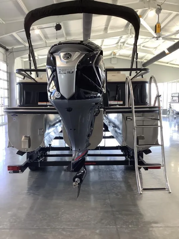 Slide: The Image of 2025 G3 Select 322SS pontoon boat with powerful outboard motor in a spacious indoor showroom. - 3